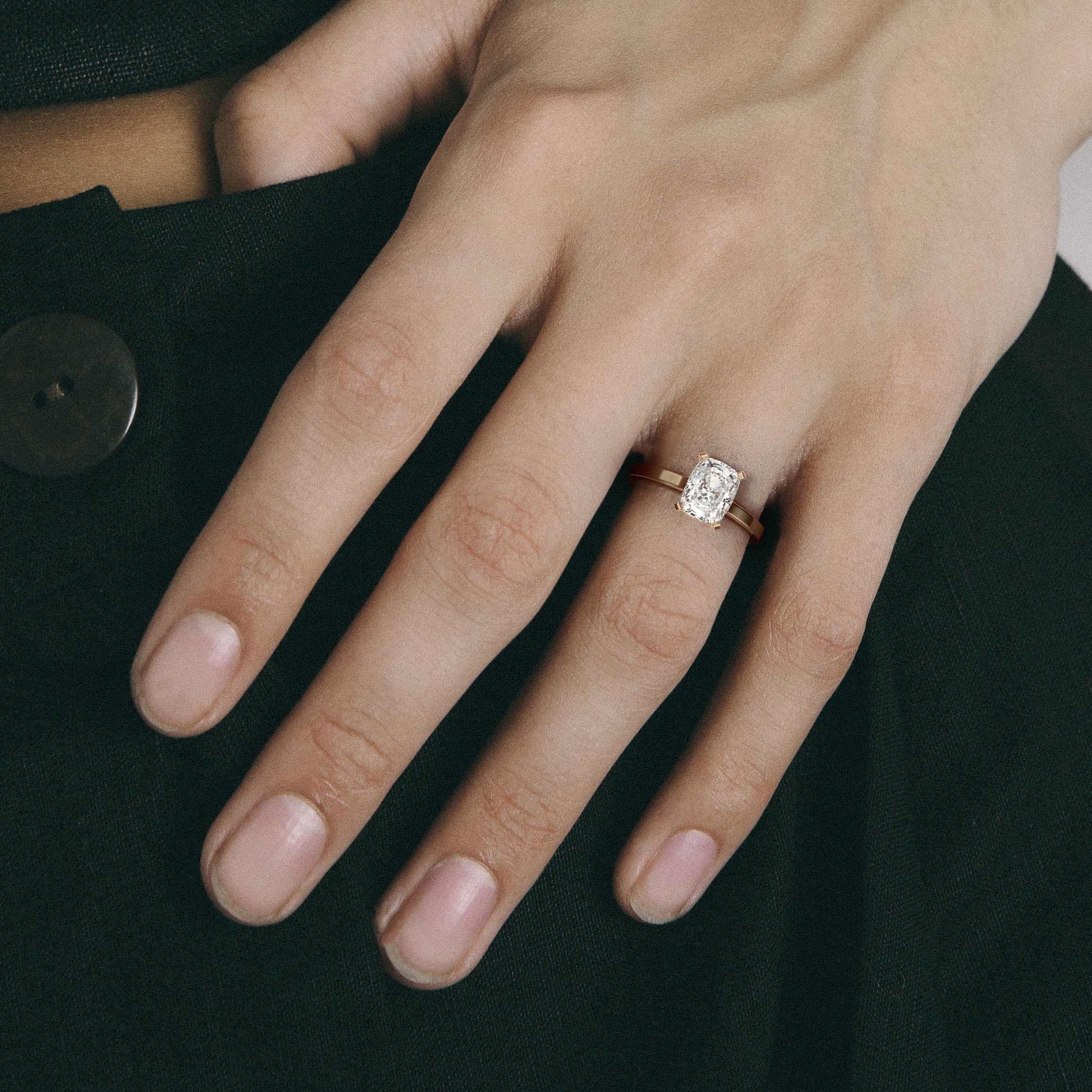 Close view of north-south cushion diamond with corner prongs on slim flat band