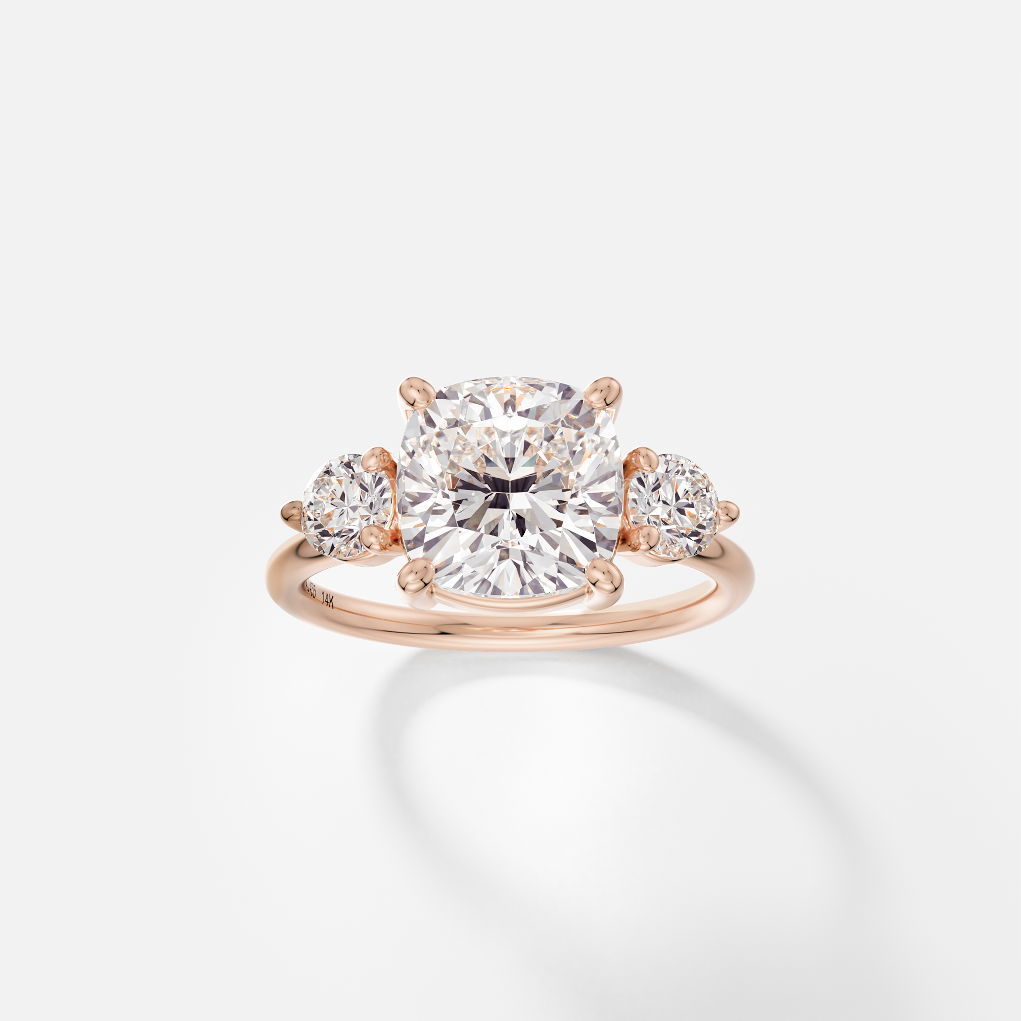 14k rose gold engagement ring with 3.25 carat cushion diamond and round side stones in corner prong setting
