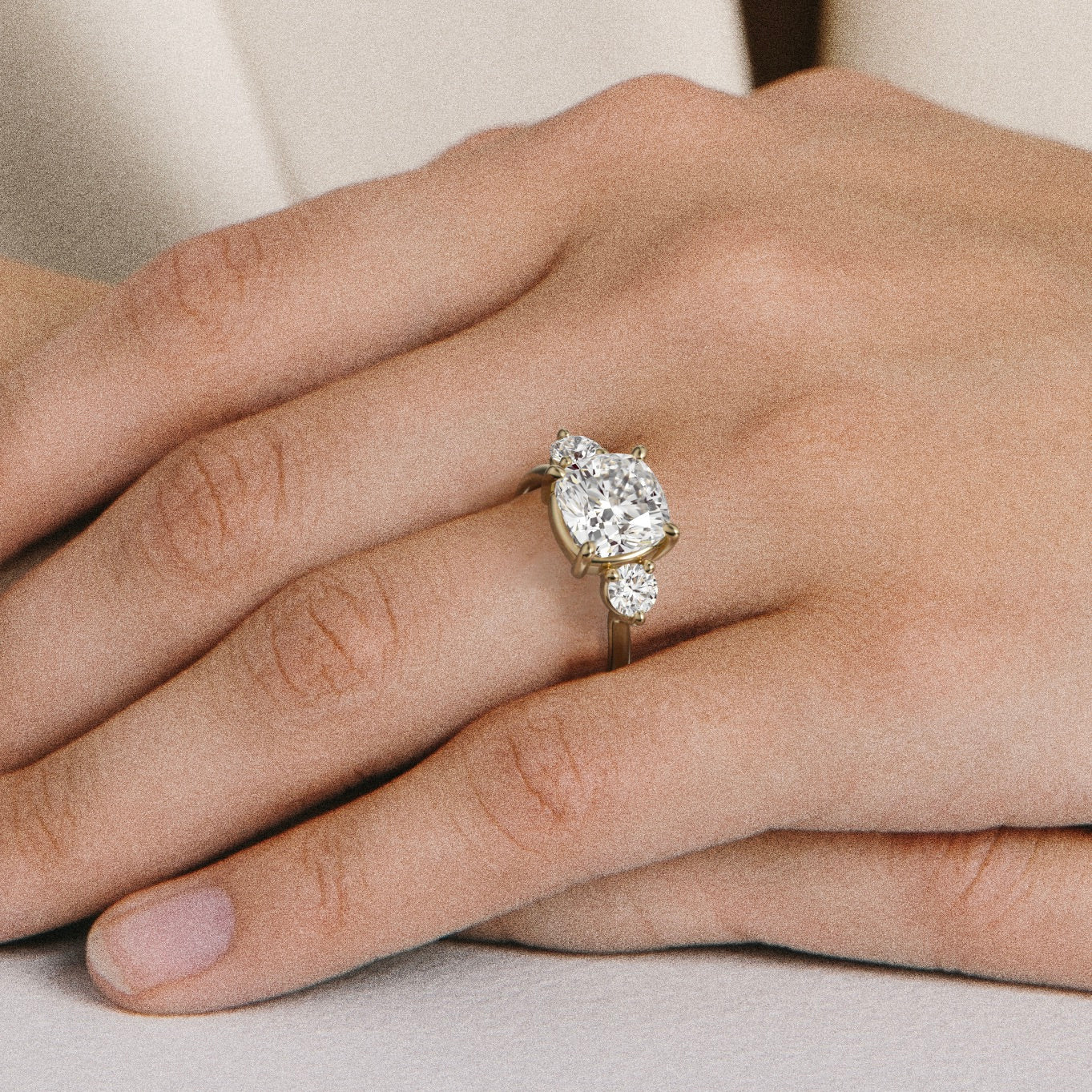 Close view of cushion-cut diamond three stone engagement ring with round side stones on delicate band