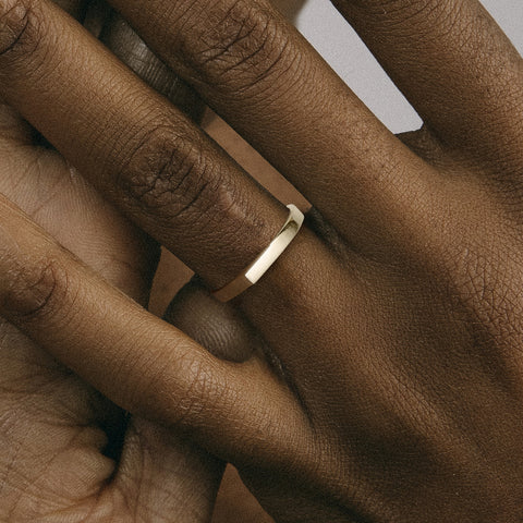 2.5mm flat gold band with defined peak worn on hand