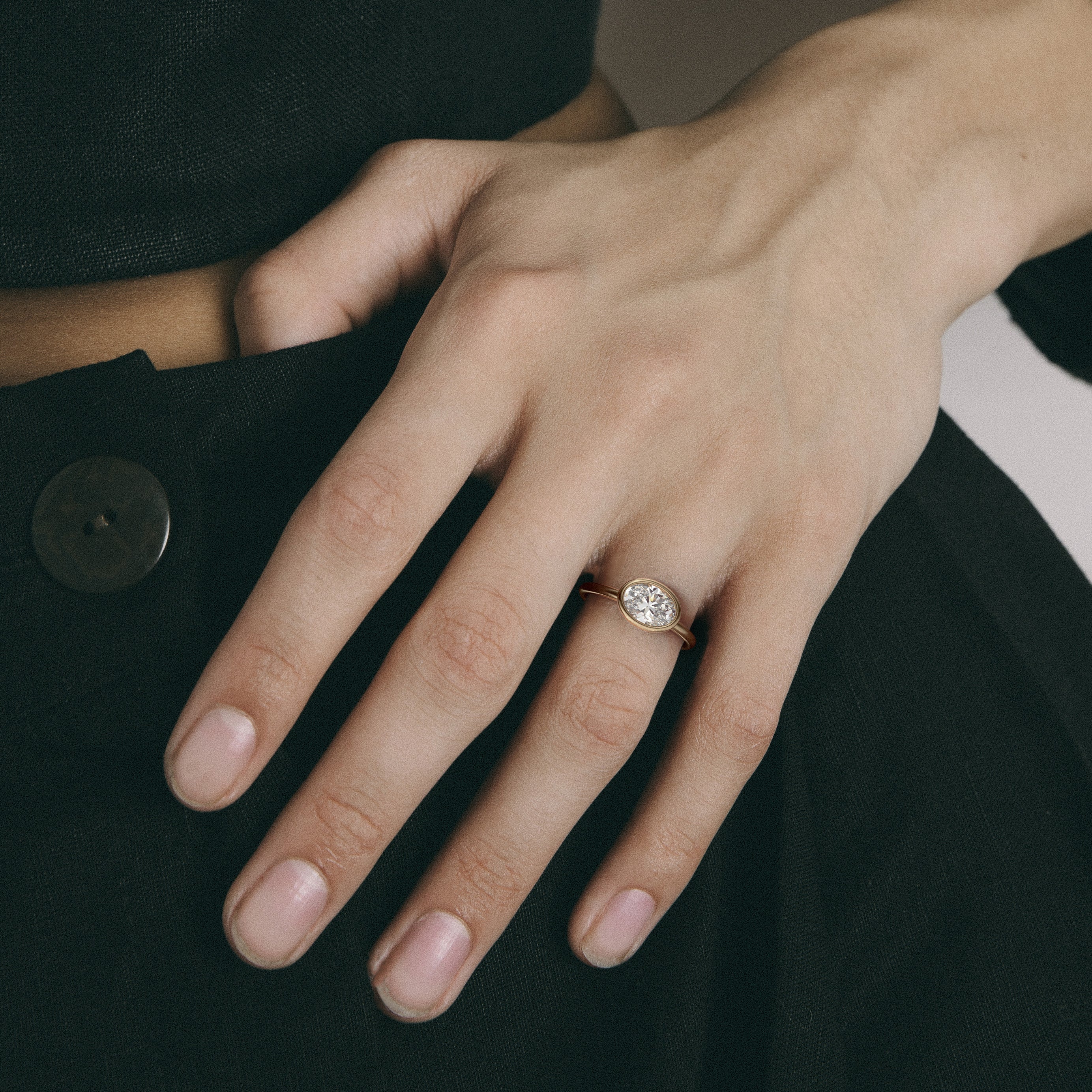 Close view of oval diamond in thin bezel on slim round profile band