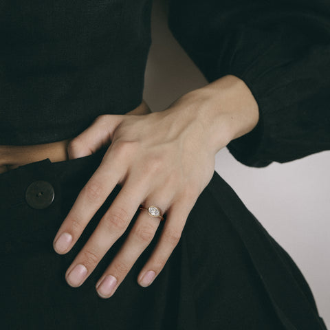 14k yellow gold engagement ring with oval diamond set east west in thin bezel worn on hand