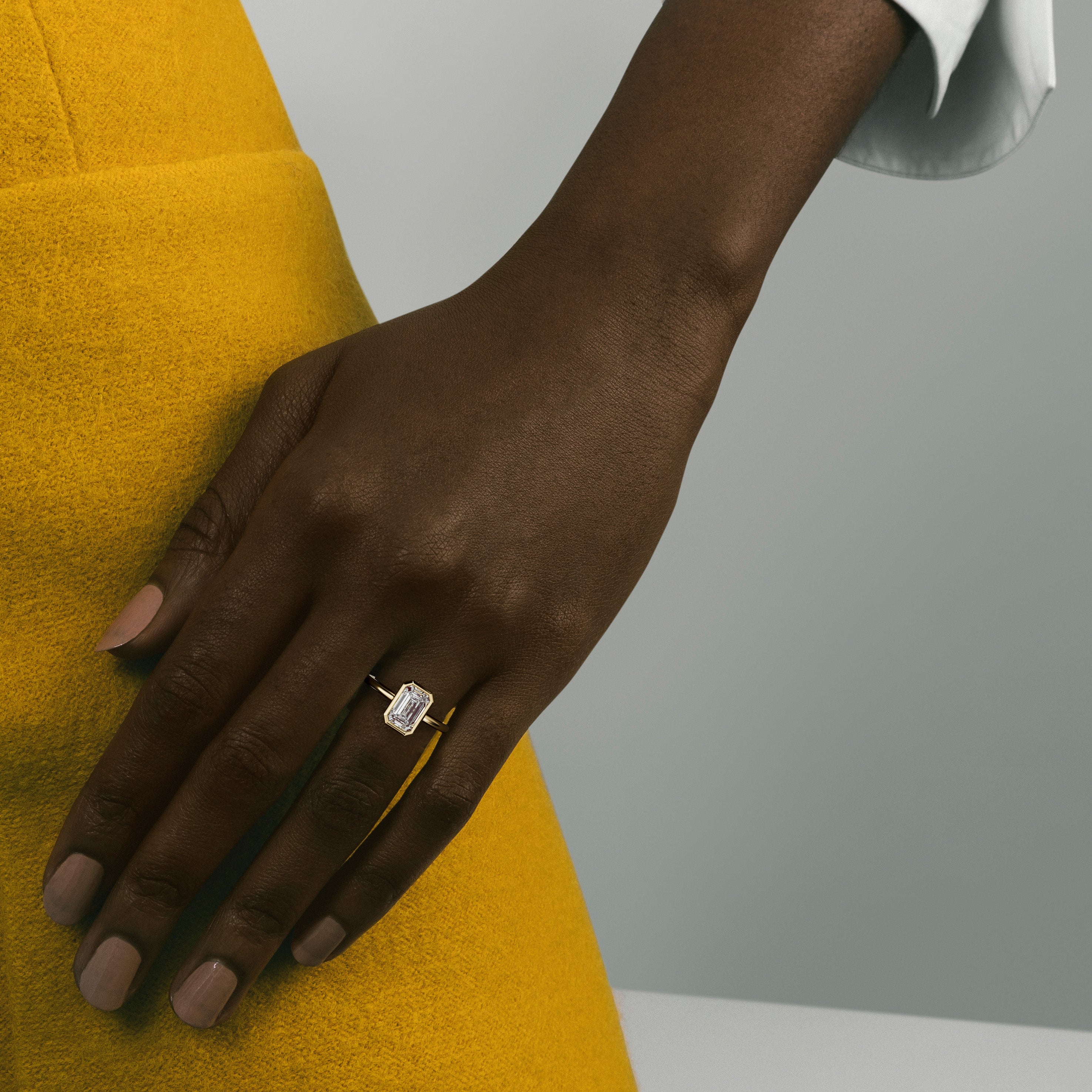 Yellow gold engagement ring with 2 carat round diamond in thin bezel worn on hand