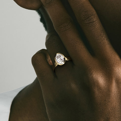 Close view of oval diamond in thin bezel on wide flat band