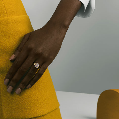 Sculptural yellow gold engagement ring with emerald-cut diamond worn on hand