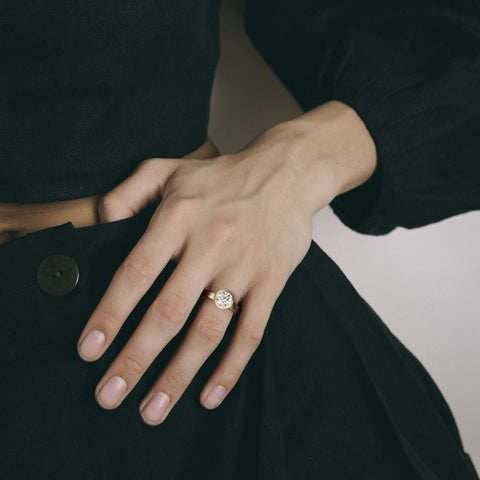 Sculptural yellow gold engagement ring with round diamond worn on hand