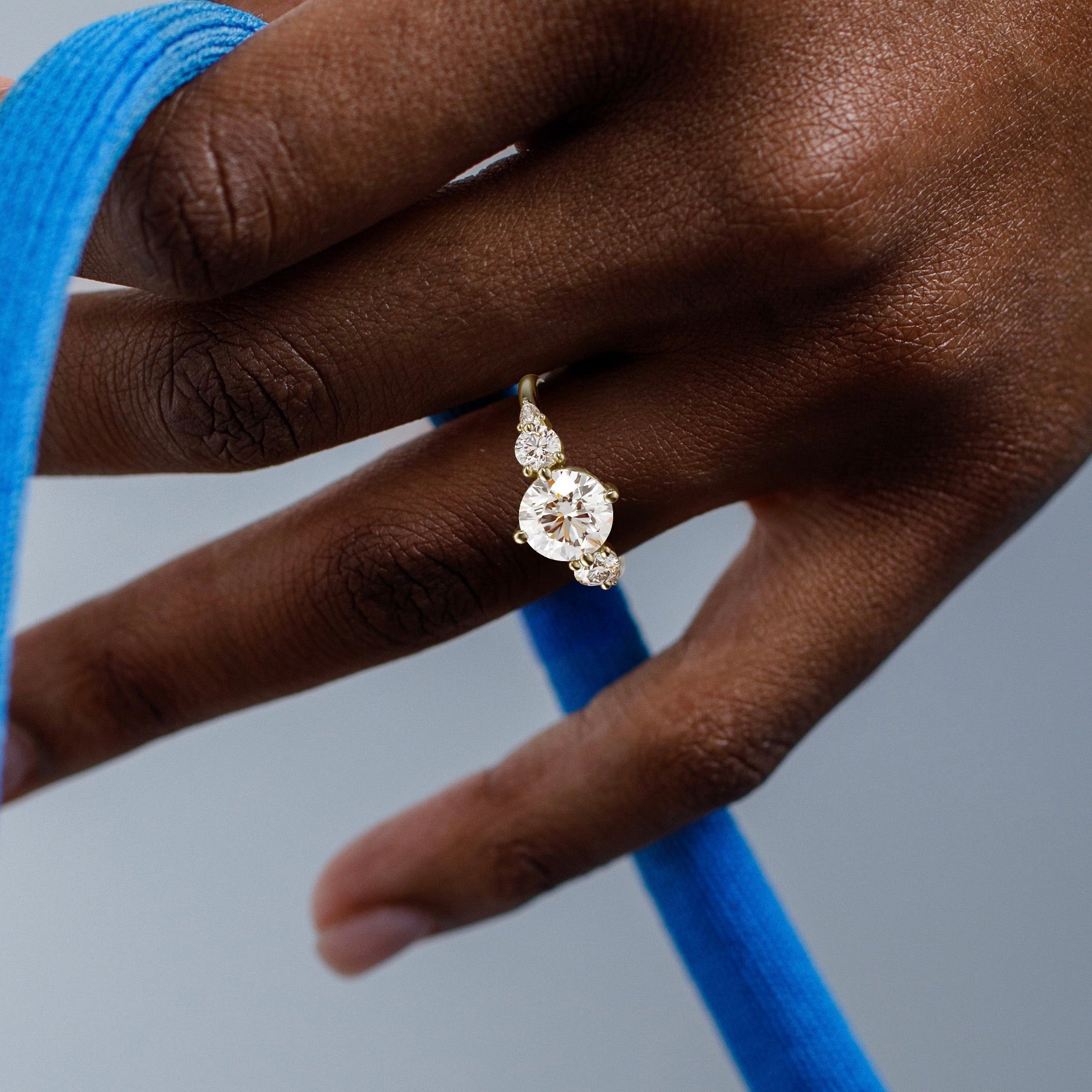 close view of round brilliant diamond five stone engagement ring with pear and round accent stones on thin band