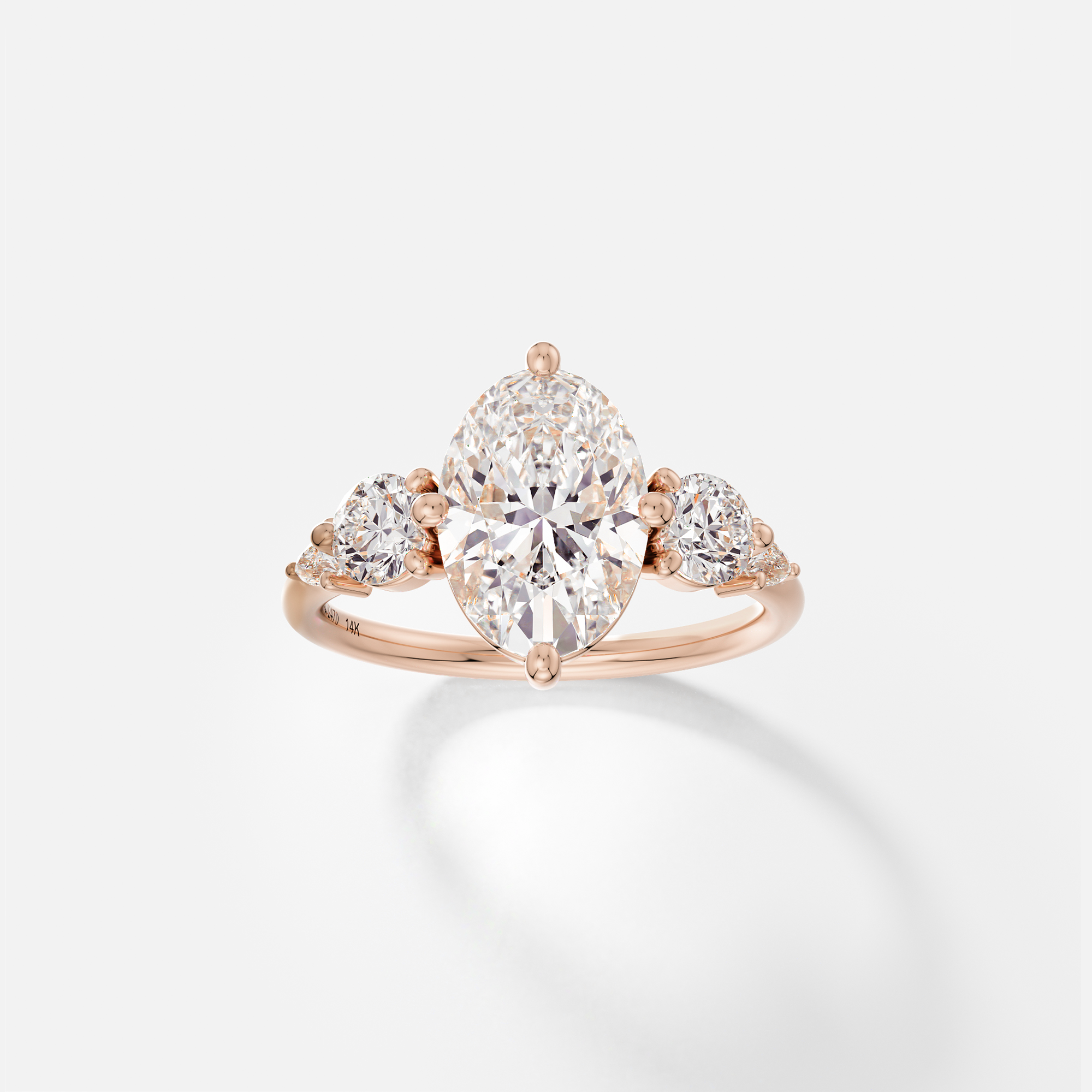 14k rose gold engagement ring with 2.50 carat oval diamond and pear and round accent stones in five stone cluster setting