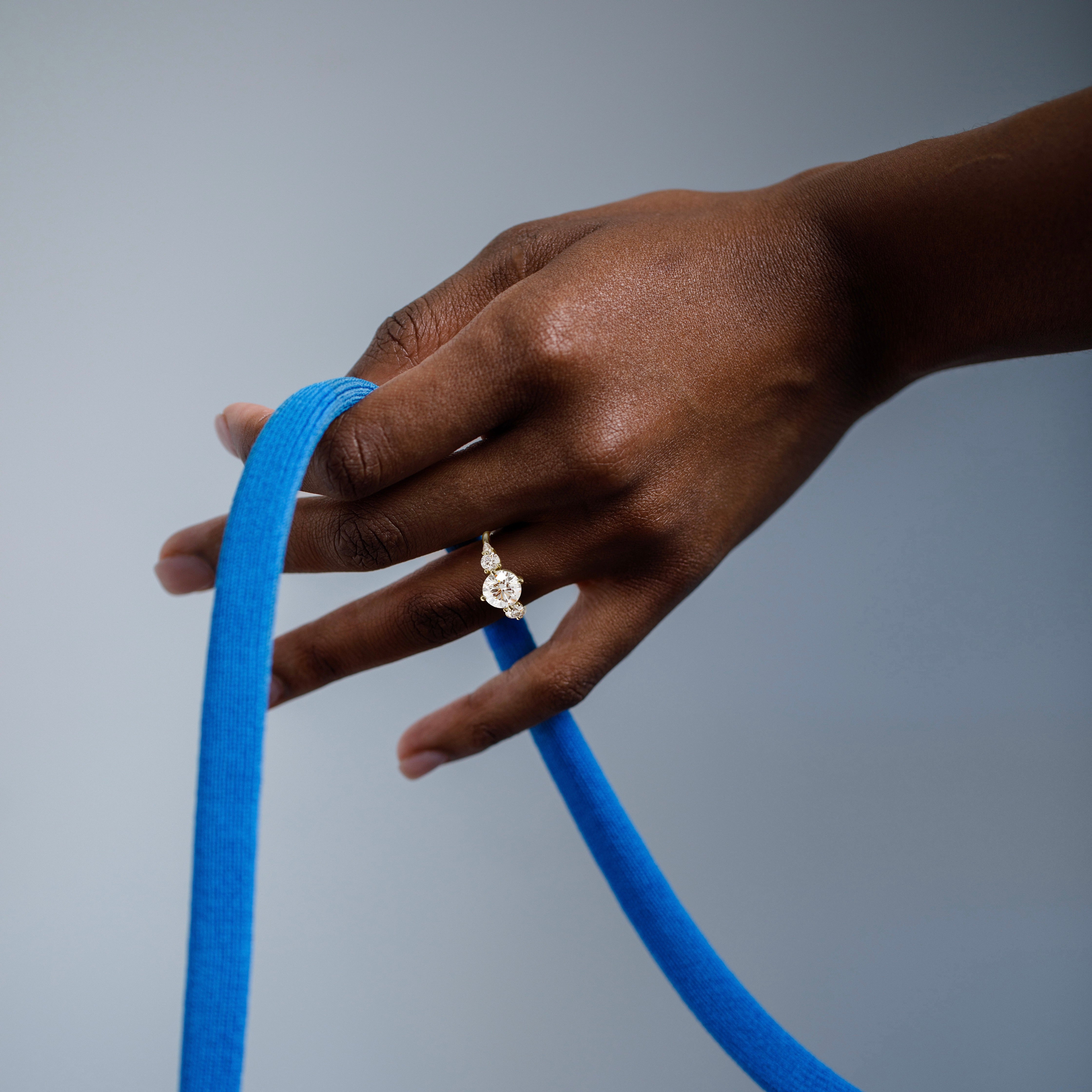 2.50 carat round brilliant diamond five stone cluster engagement ring with pear and round side stones worn on hand