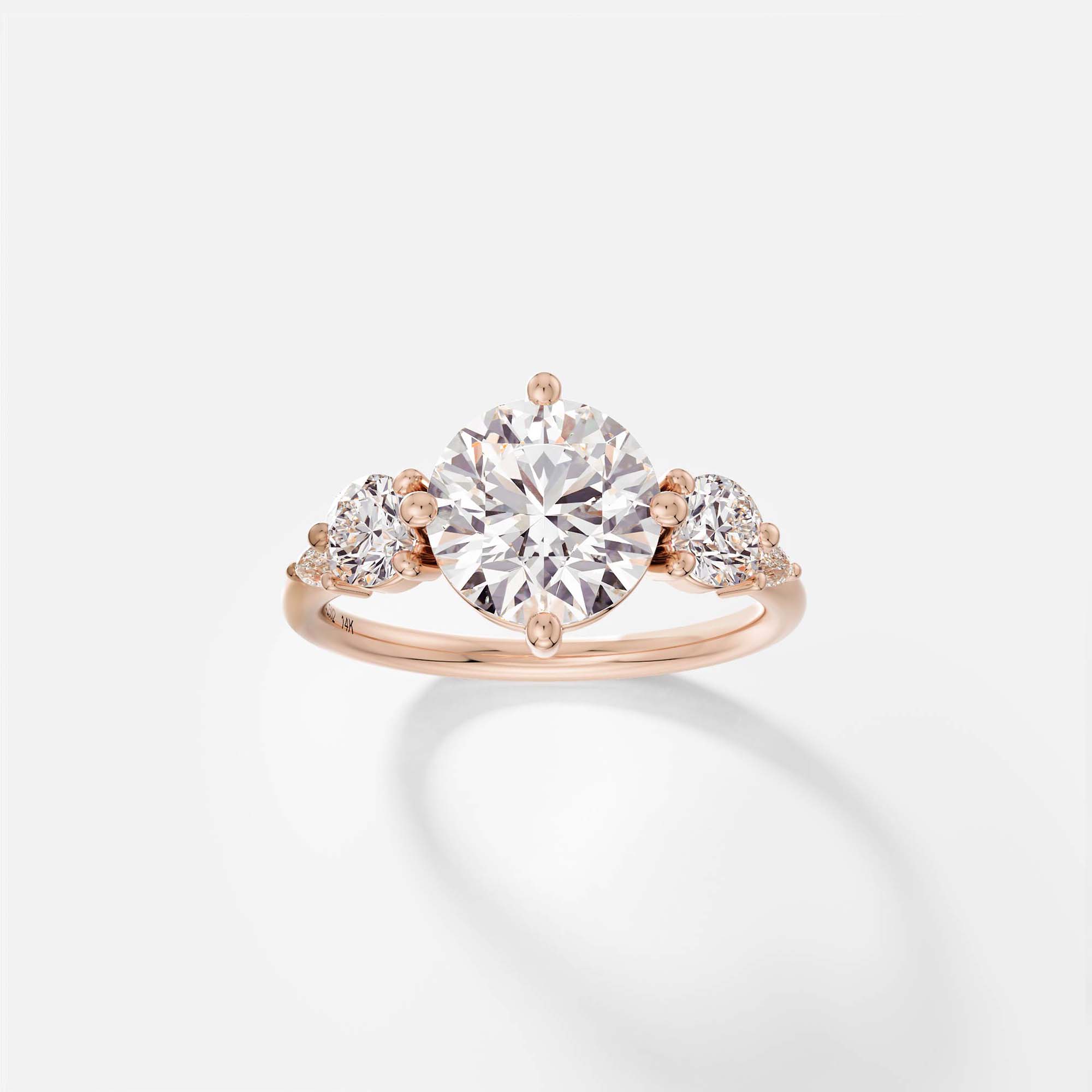 14k rose gold engagement ring with 2.50 carat round brilliant diamond and pear and round accent stones in five stone cluster setting