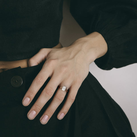 Dainty yellow gold engagement ring with cushion diamond worn on hand