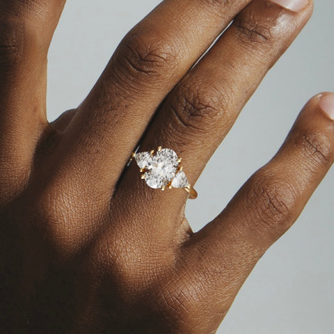 close view of oval diamond three stone engagement ring with trillion side stones on round band