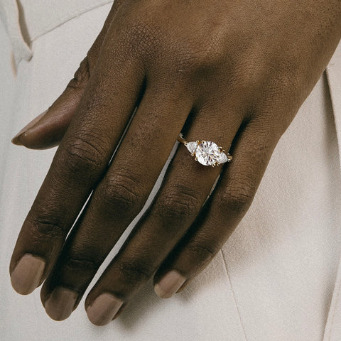 close view of round brilliant diamond three stone engagement ring with trillion side stones on round band