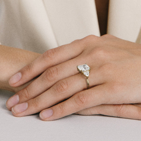 close view of 3.50 ct cushion diamond three stone engagement ring with trillion side stones on round band