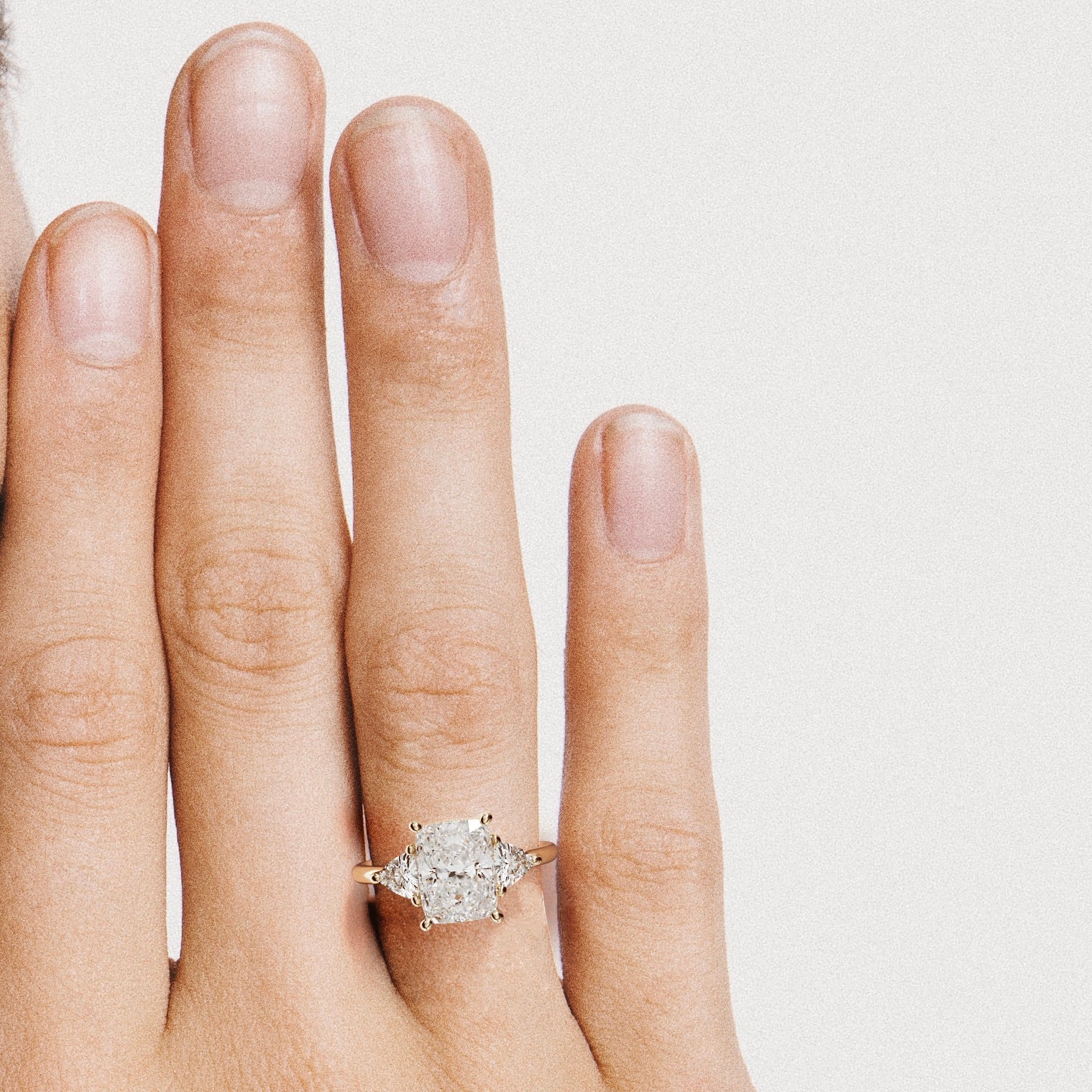 close view of elongated cushion diamond three stone engagement ring with trillion side stones on round band