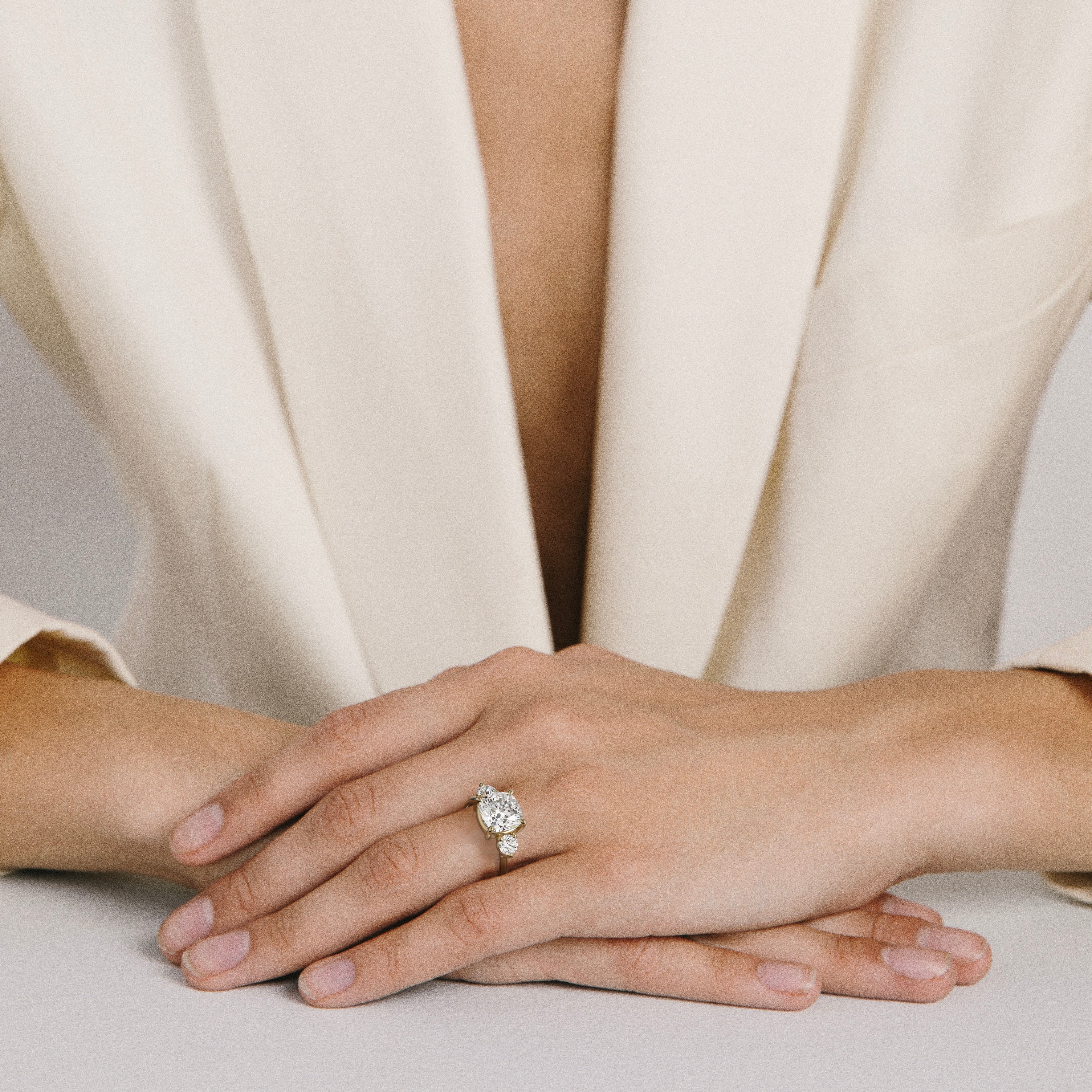 Kala cushion diamond three stone engagement ring worn on hand