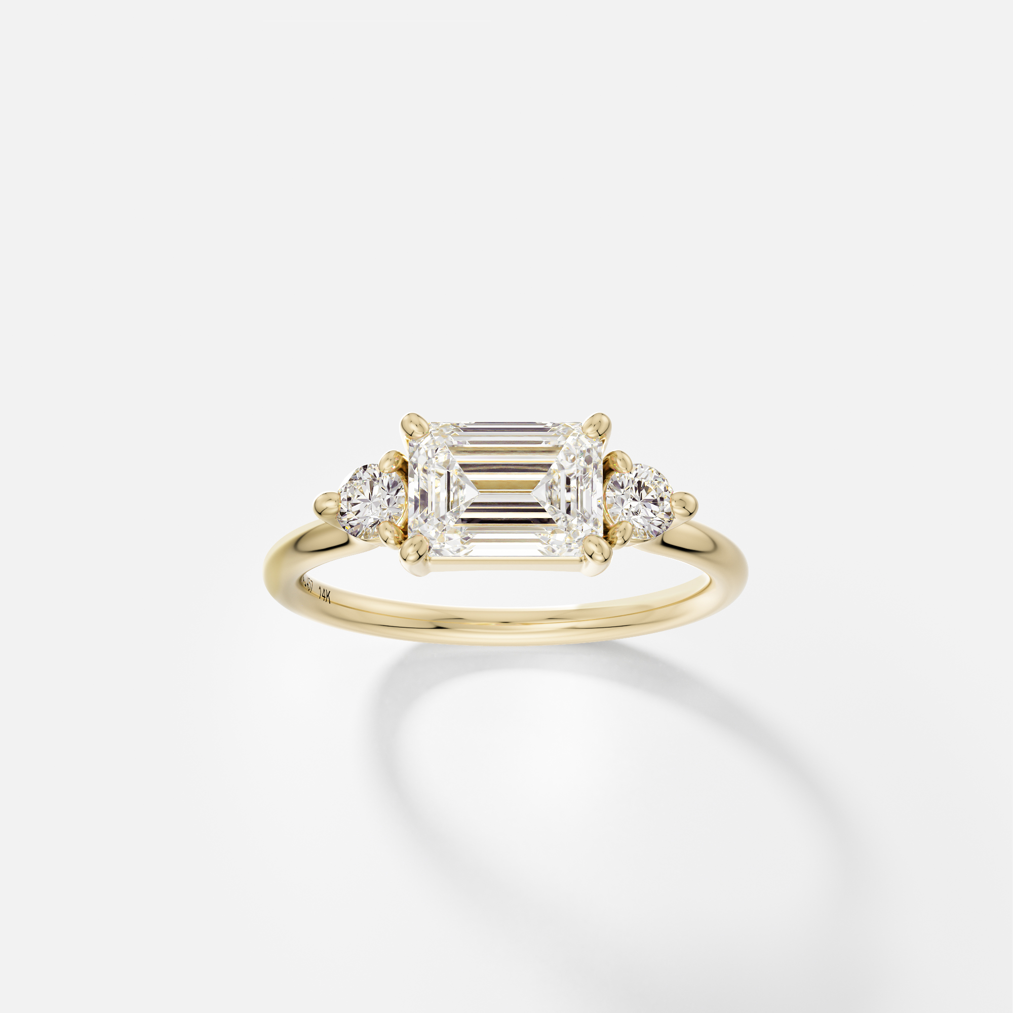 14k yellow gold three stone engagement ring with 1.50 carat emerald-cut diamond set east-west in corner prongs and round side stones