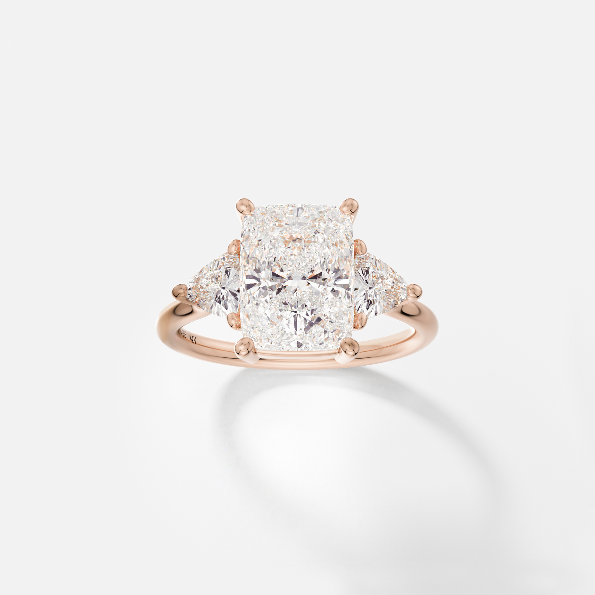 14k rose gold engagement ring with 3 carat elongated cushion diamond and trillion-cut side stones in corner prongs