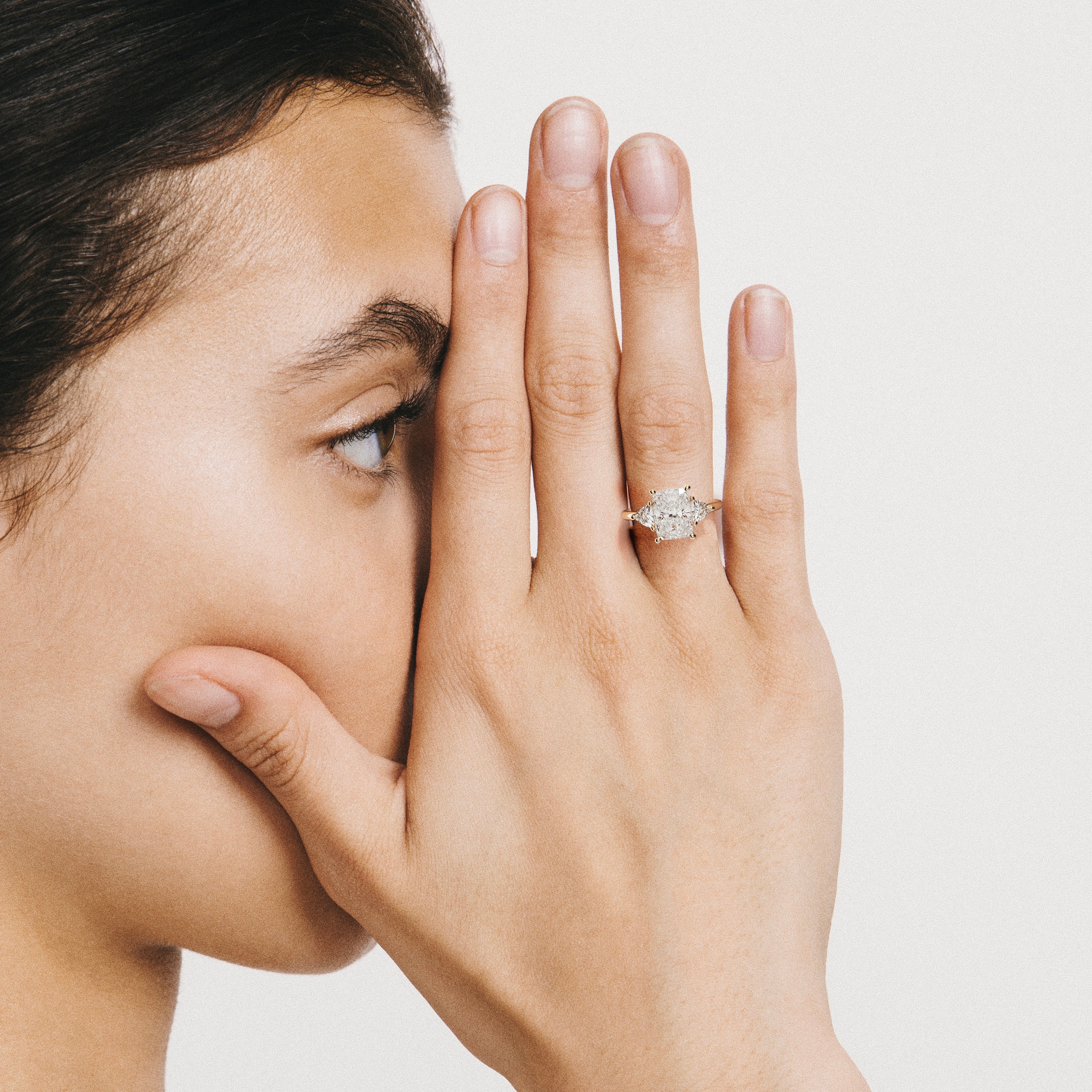 3 carat elongated cushion diamond engagement ring with trillion side stones worn on hand