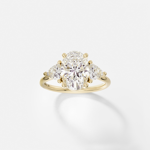 14k yellow gold three stone engagement ring with 2.50 carat oval diamond and trillion-cut side stones in corner prong setting