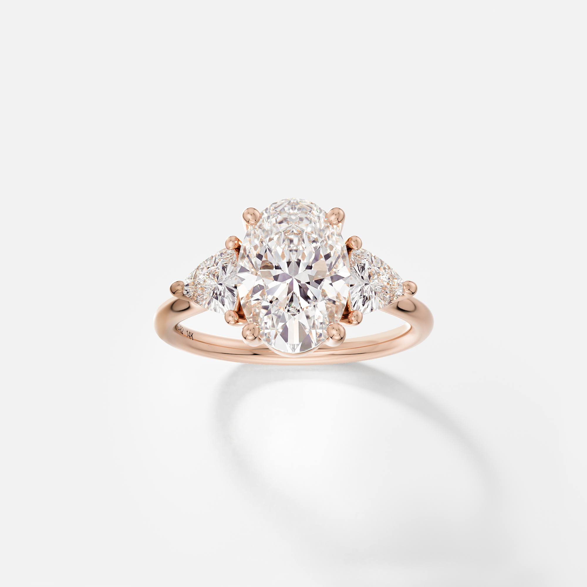 14k rose gold engagement ring with 2.5 carat oval diamond and trillion-cut side stones in corner prongs