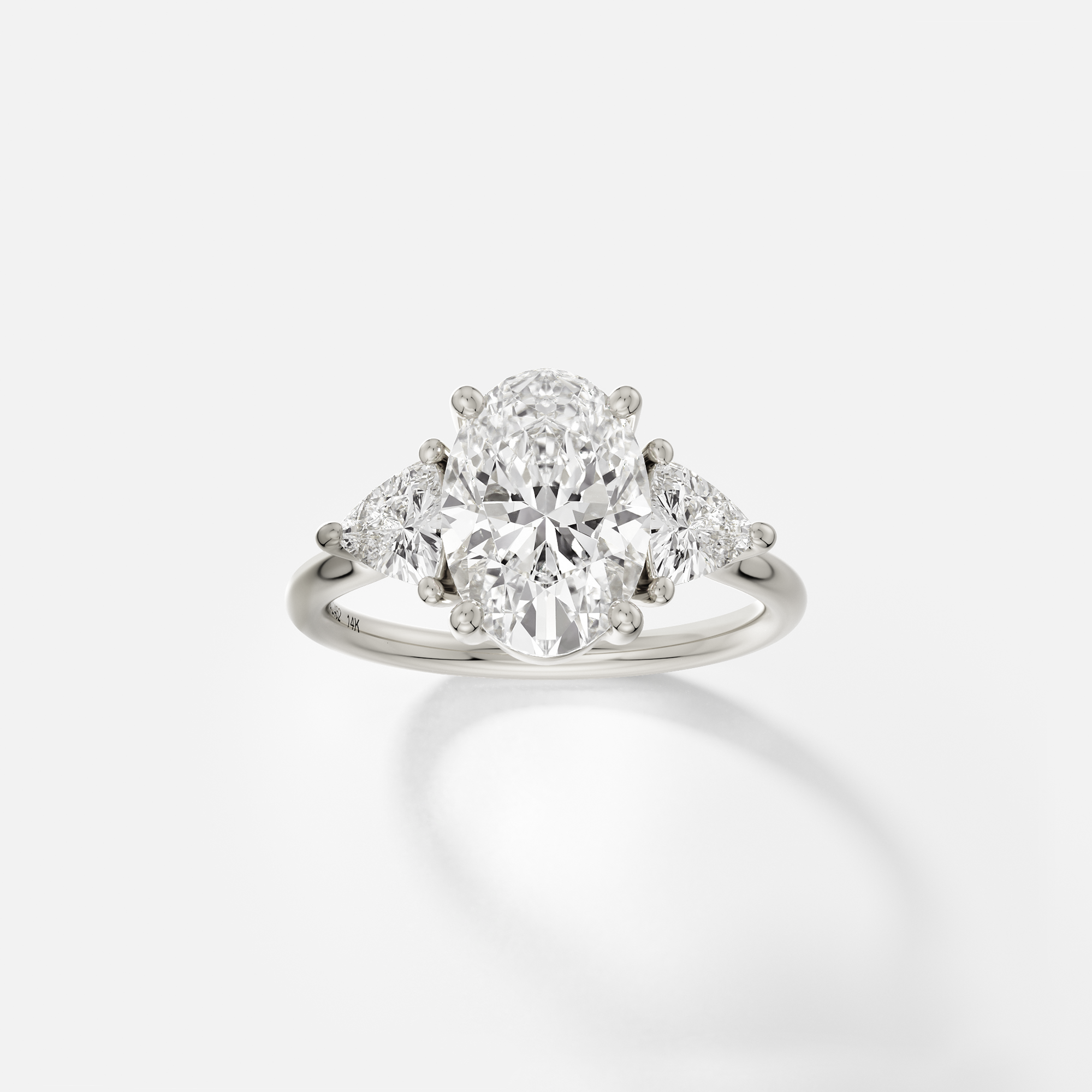 14k white gold engagement ring with 2.50 ct oval diamond and trillion side stones in prong setting