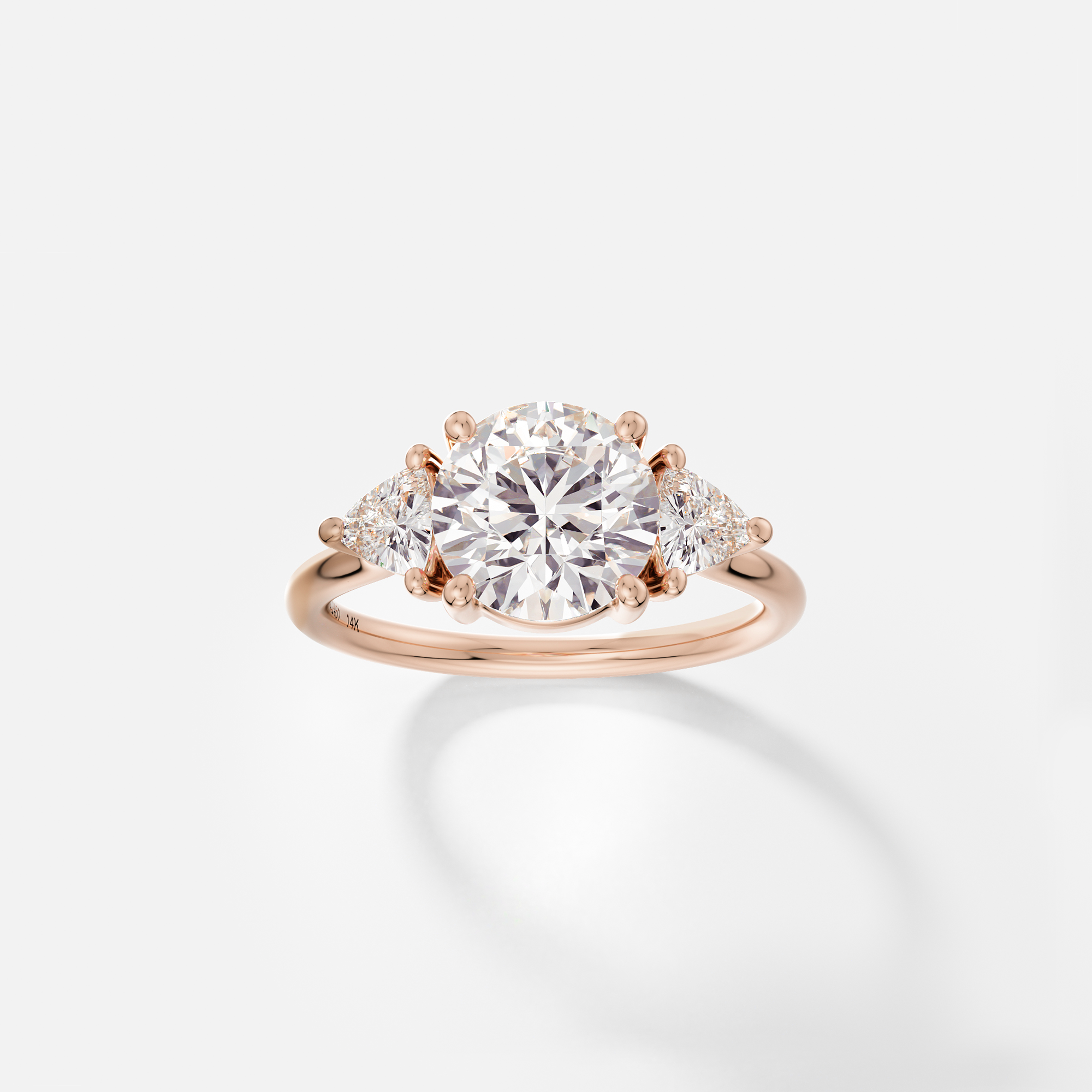14k rose gold engagement ring with 2 carat round brilliant diamond and trillion-cut side stones in corner prongs