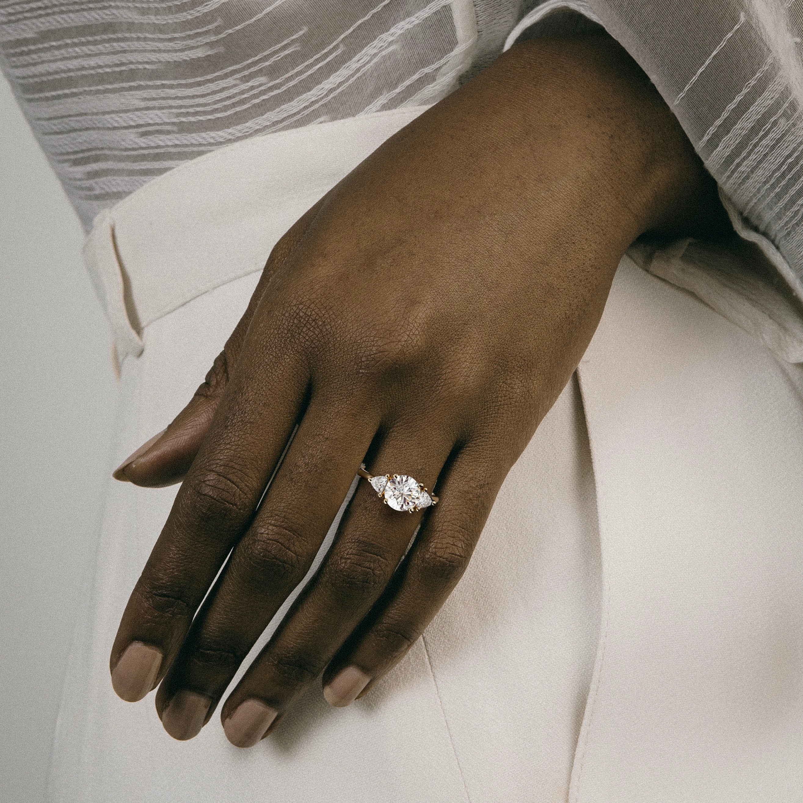 2.00 carat round brilliant diamond engagement ring with trillion side stones worn on hand