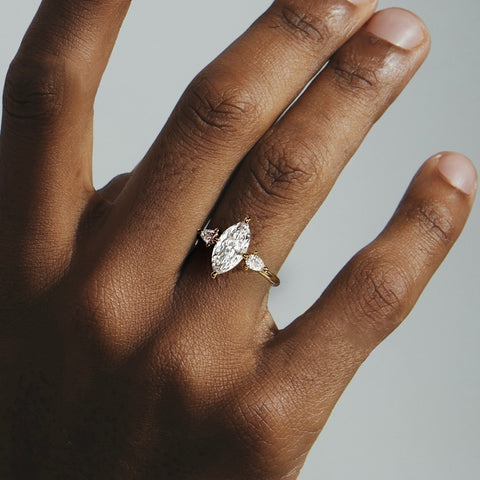 close view of marquise diamond three stone engagement ring with pear-cut side stones on thin round band