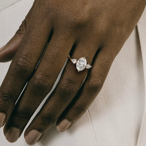 close view of oval diamond three stone engagement ring with pear-cut side stones on thin round band