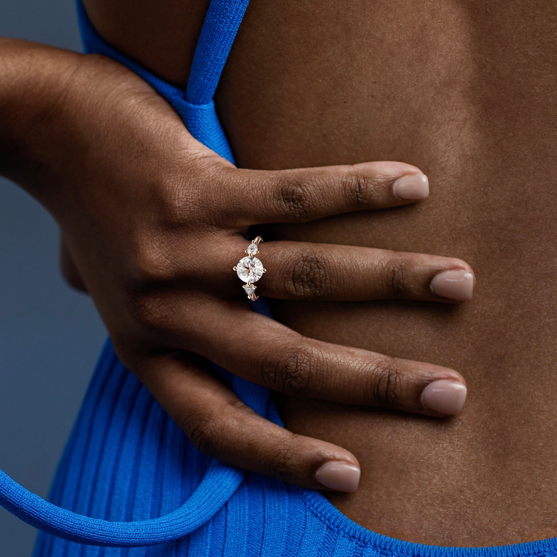 close view of round brilliant diamond three stone engagement ring with pear-cut side stones on thin round band