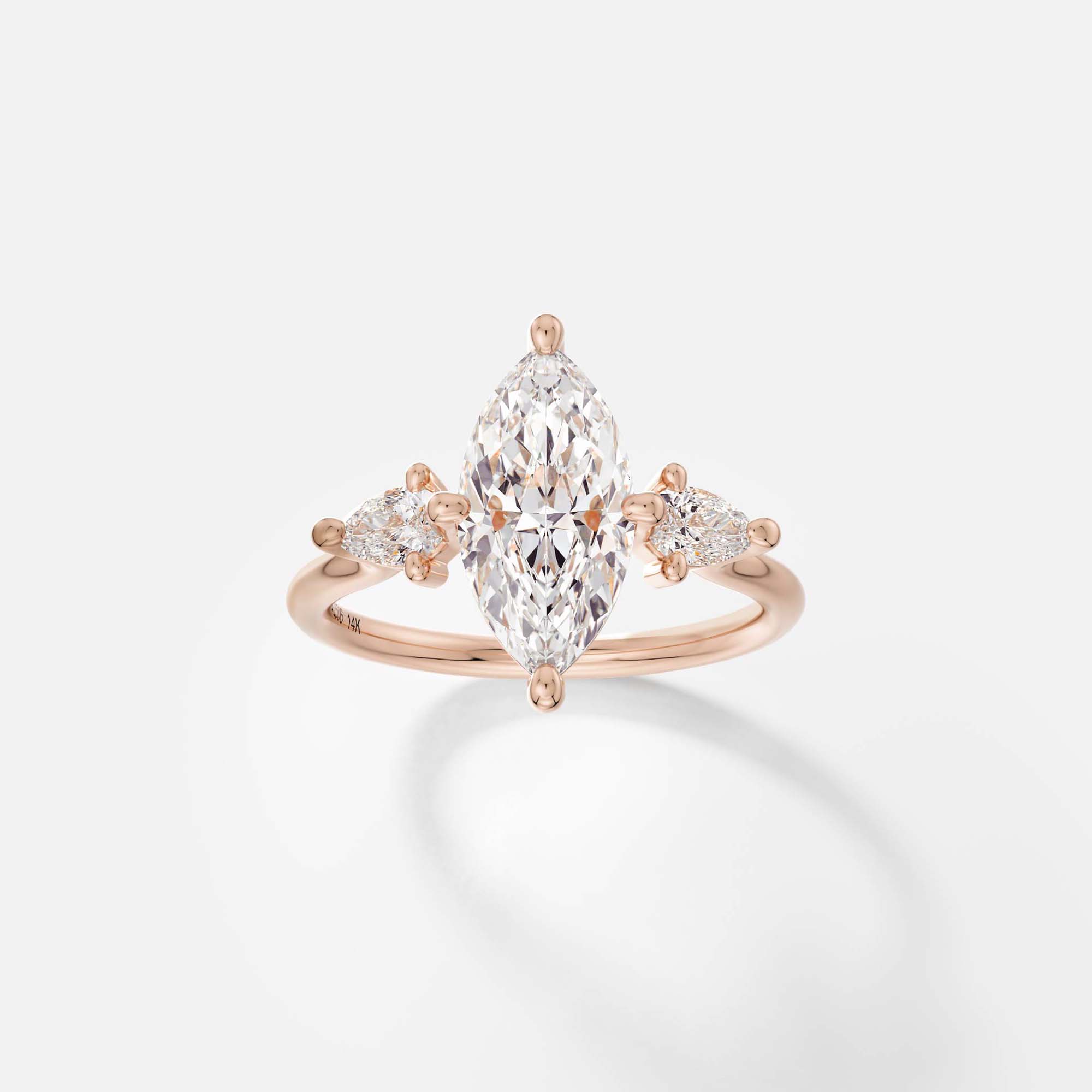14k rose gold three stone engagement ring with 2 carat marquise diamond and pear side stones on delicate round profile band