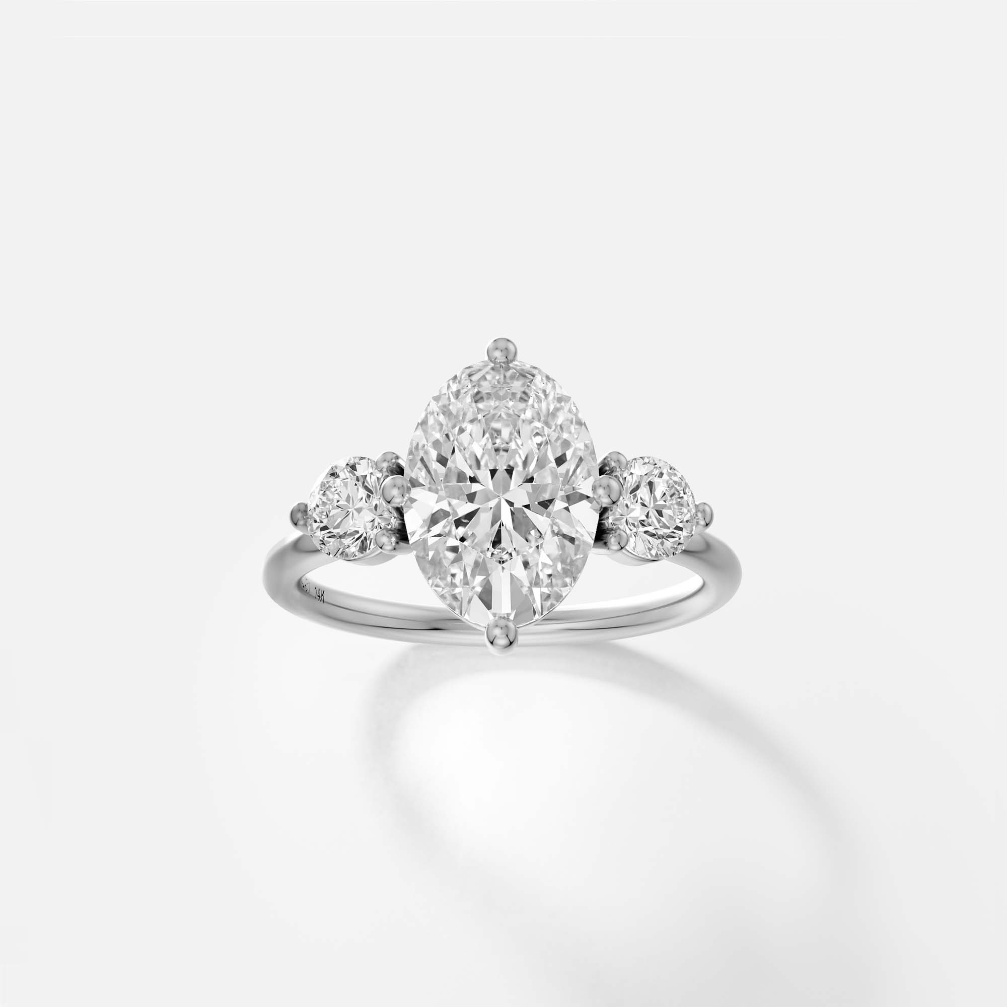 Platinum engagement ring with oval diamond center and round side diamonds in prong setting on delicate band