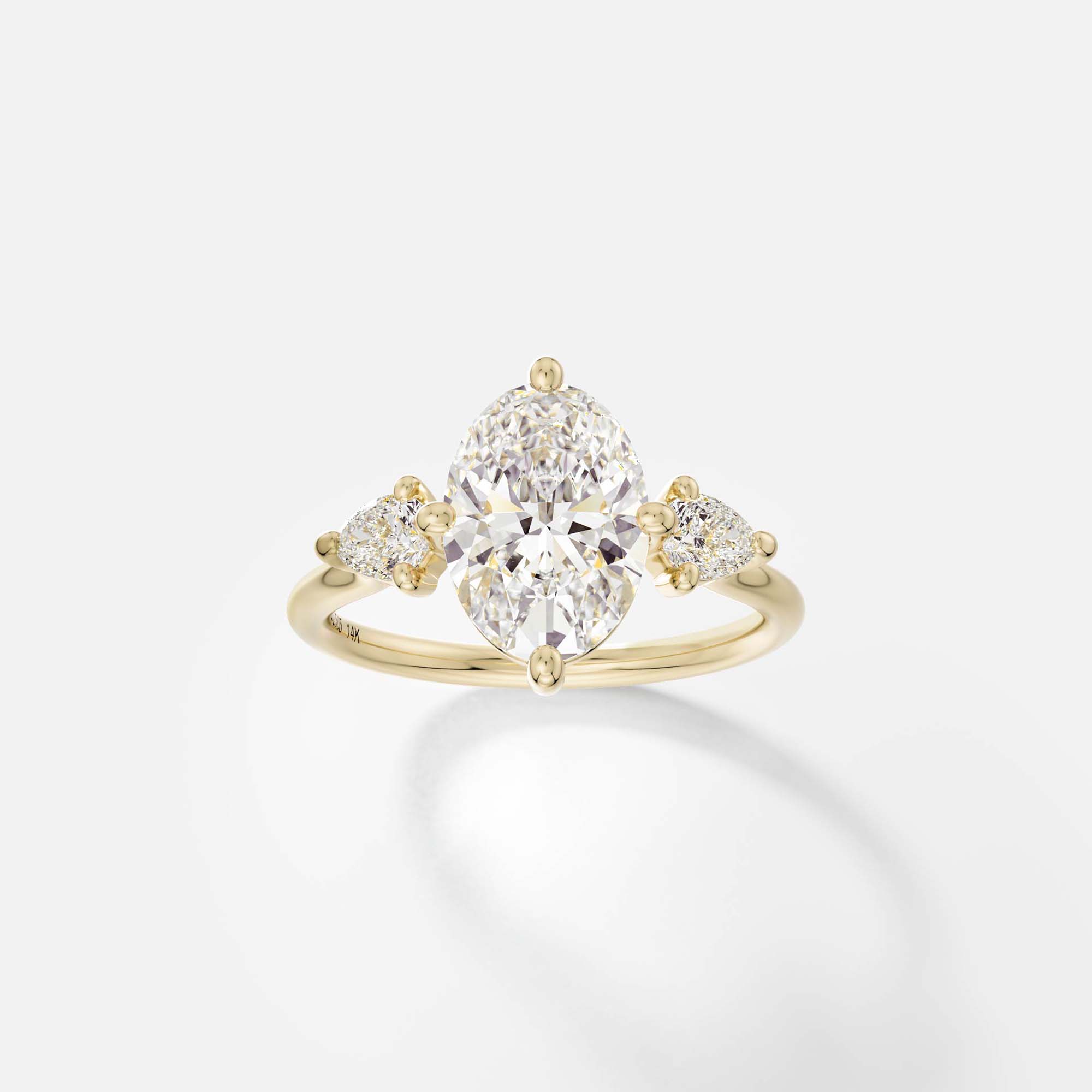 Kele oval diamond three stone engagement ring with pear side stones front view in 14k yellow gold