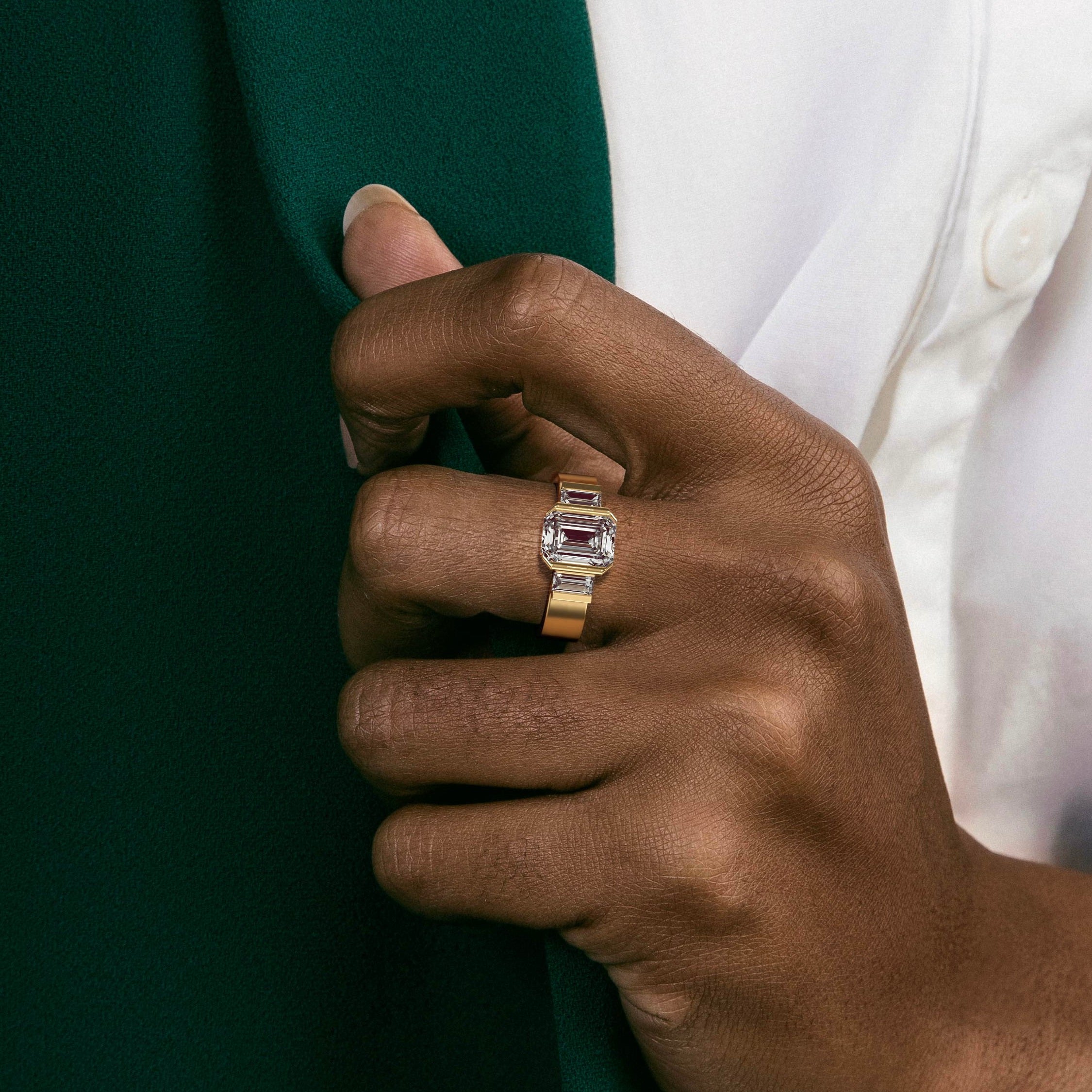 close view of emerald-cut diamond three stone ring with baguette side stones in partial bezel on flat band