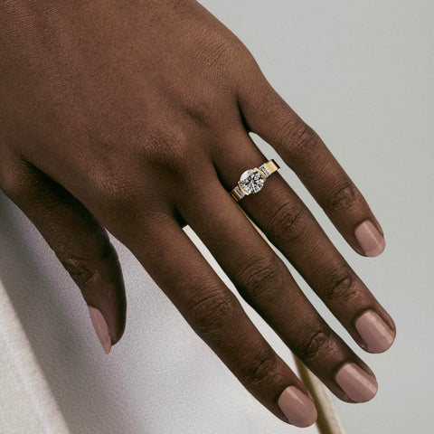 close view of round diamond three stone engagement ring with baguette side stones in partial bezel on flat band