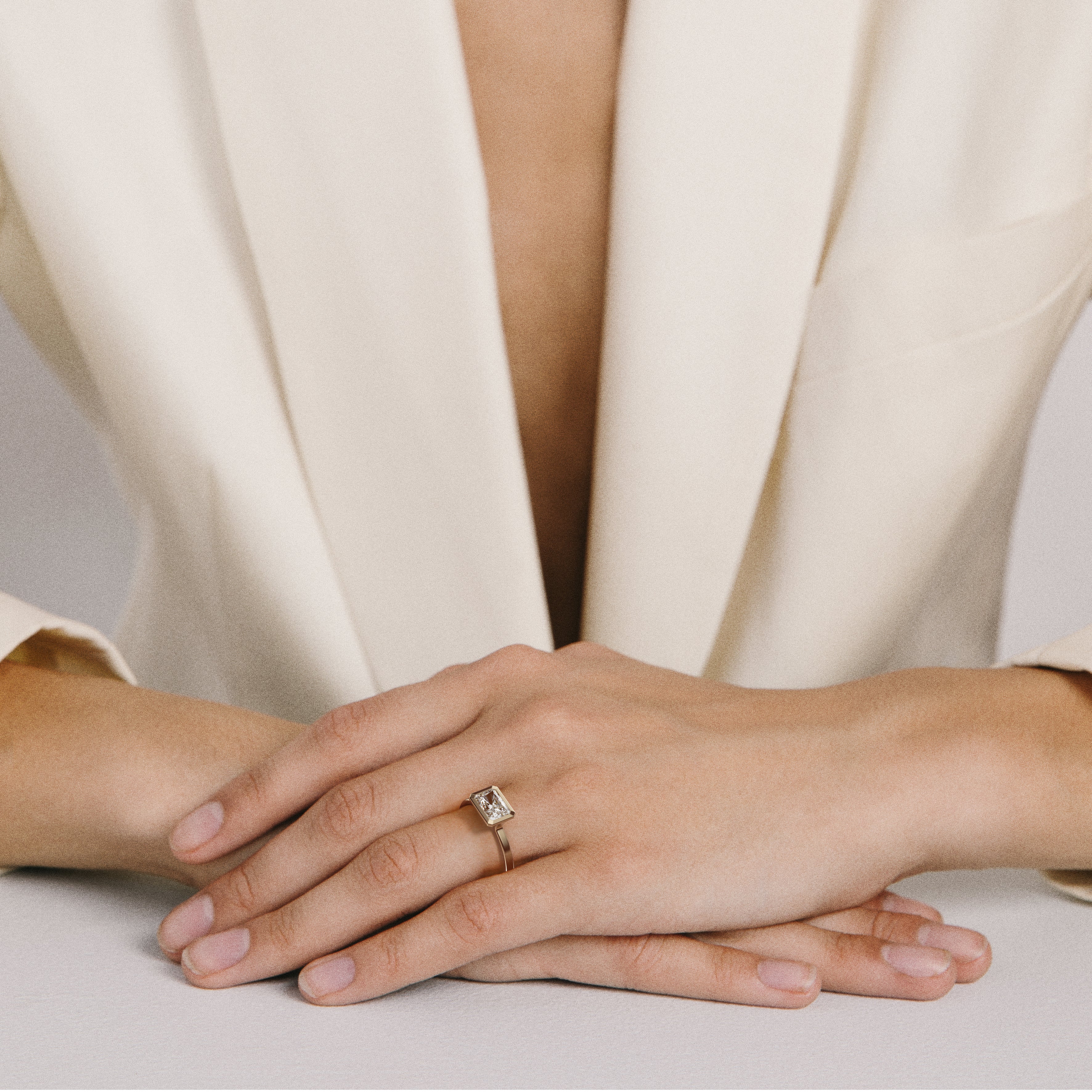 Minimal yellow gold engagement ring with bezel set radiant-cut diamond worn on hand