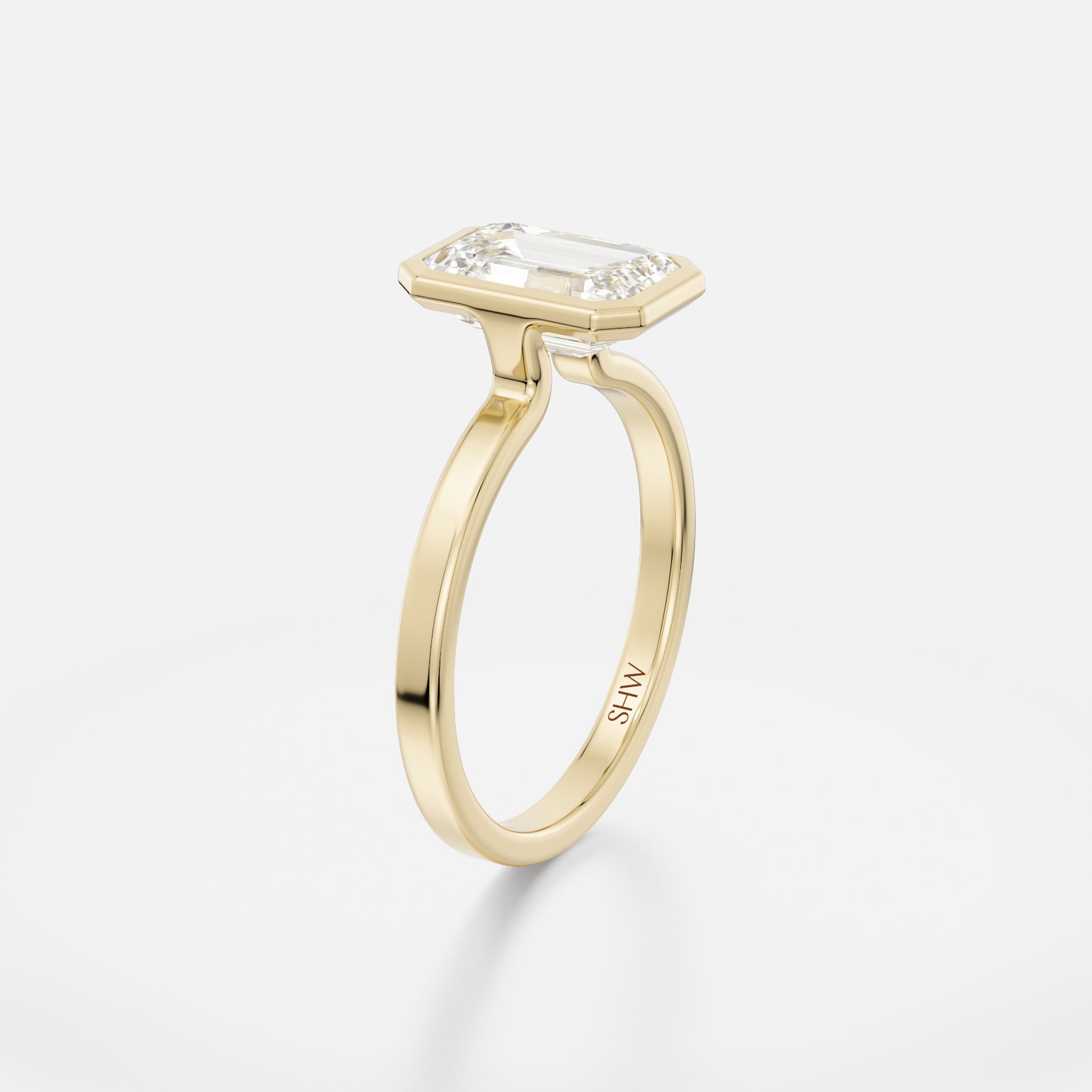 Delicate flat profile ring with thin bezel holding step-cut emerald diamond