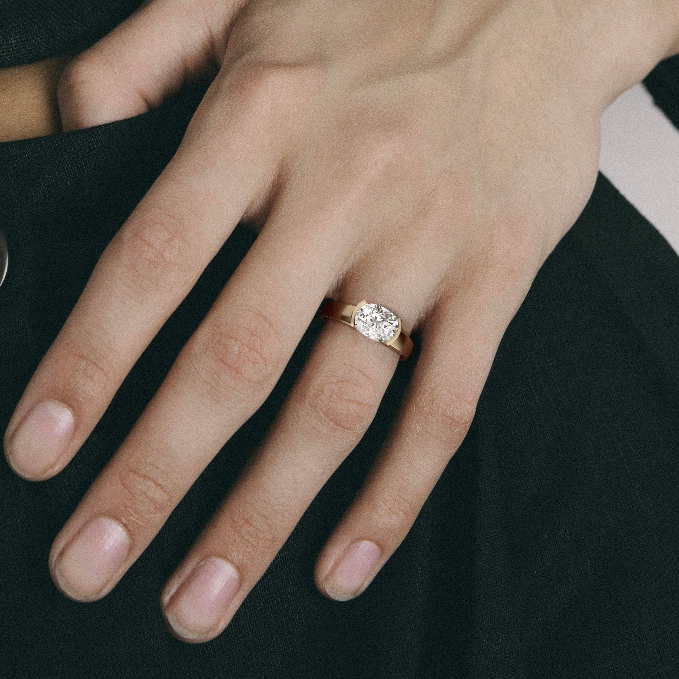 close view of east-west cushion diamond engagement ring with tapered partial bezel and narrowing band