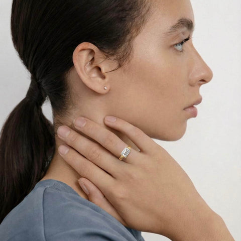 close view of east-west emerald-cut diamond engagement ring with tapered partial bezel and narrowing band