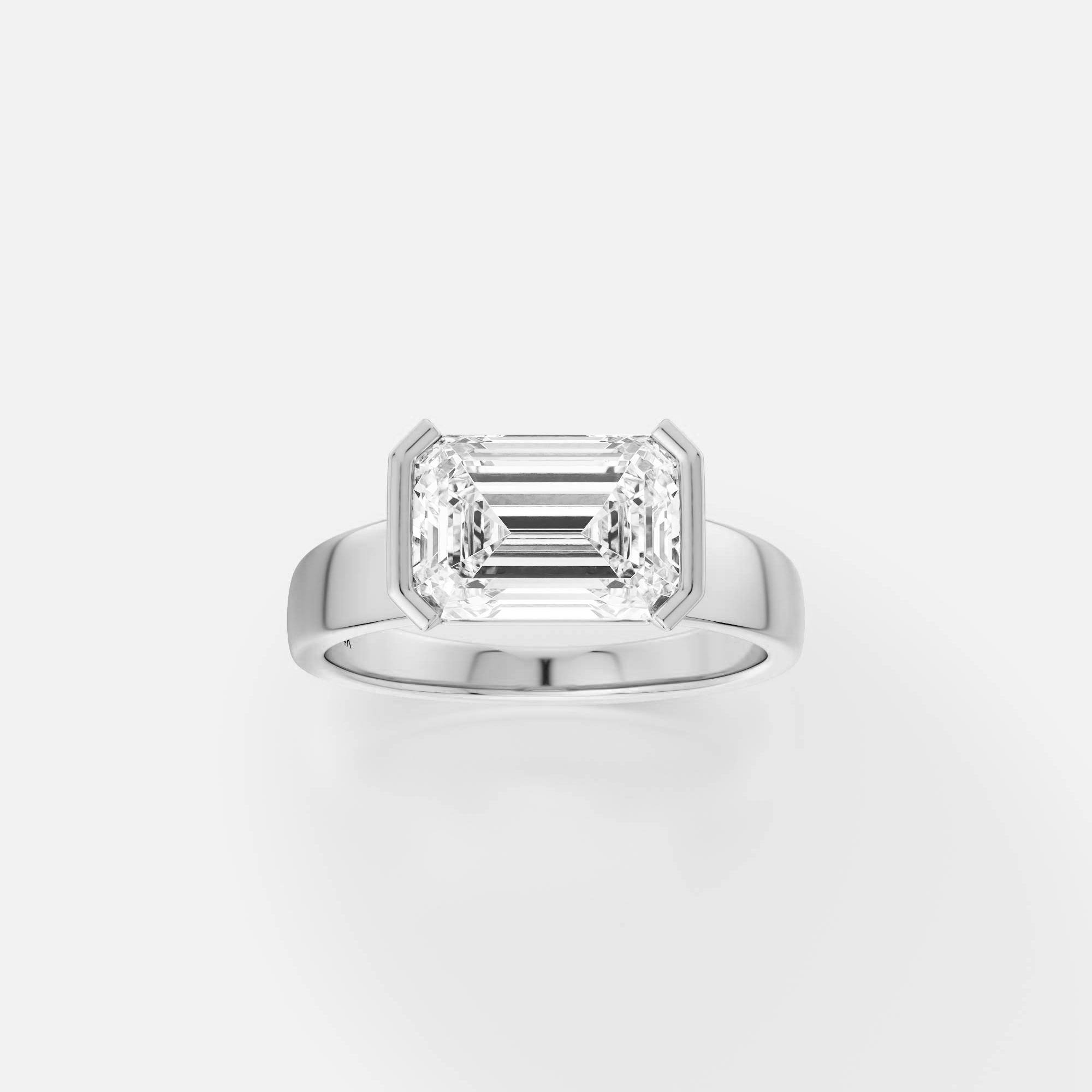 platinum engagement ring with east-west emerald-cut diamond in tapered partial bezel on modern band