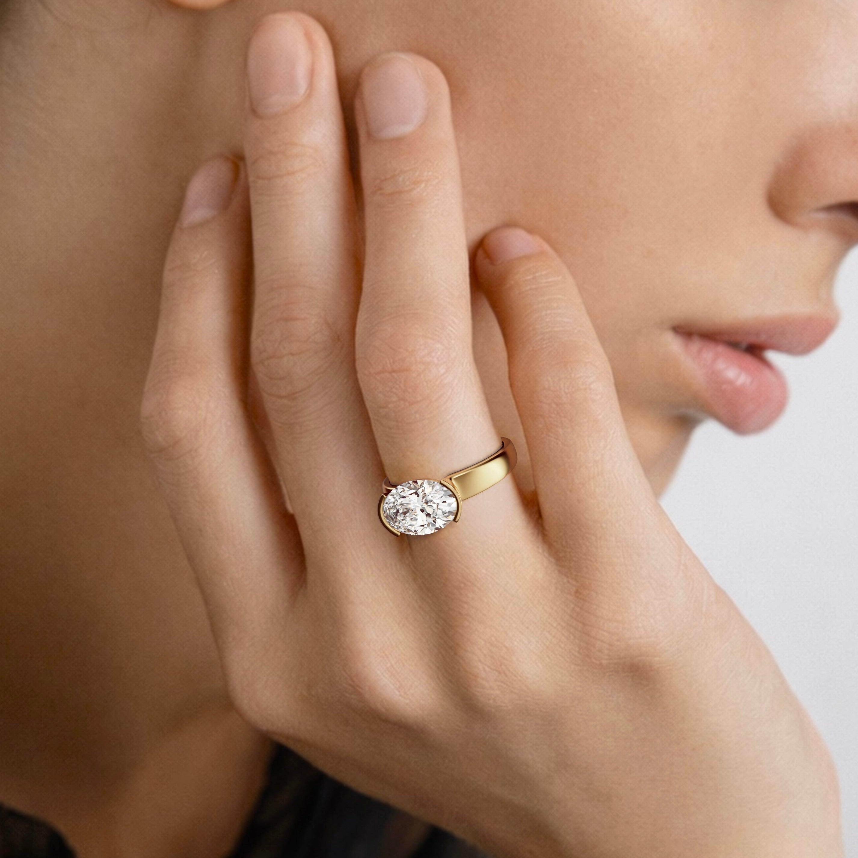 2.75 carat east-west oval diamond engagement ring with tapering partial bezel worn on hand