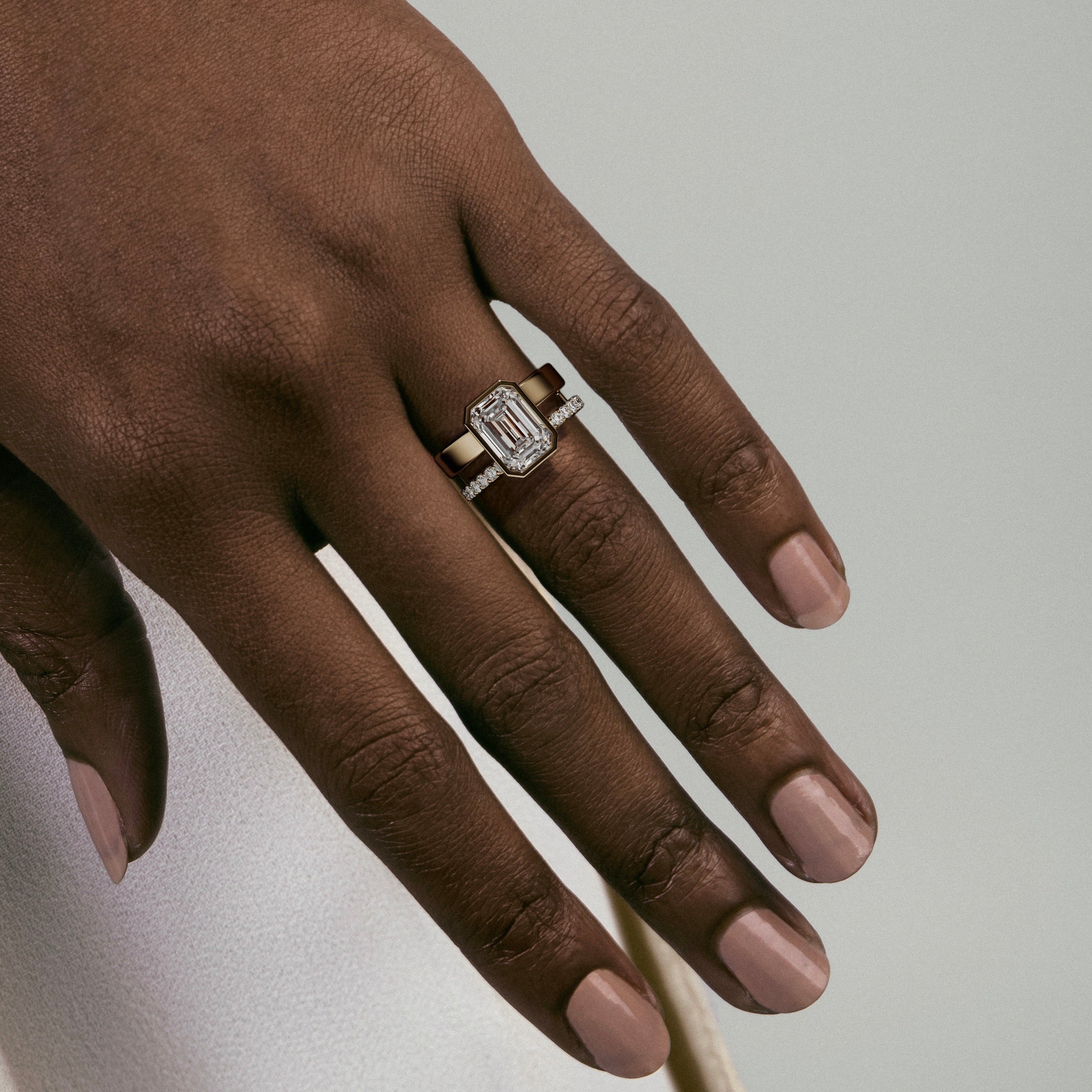 close view of 4.00 ct emerald-cut diamond bezel engagement ring with pavé diamond eternity band on double band