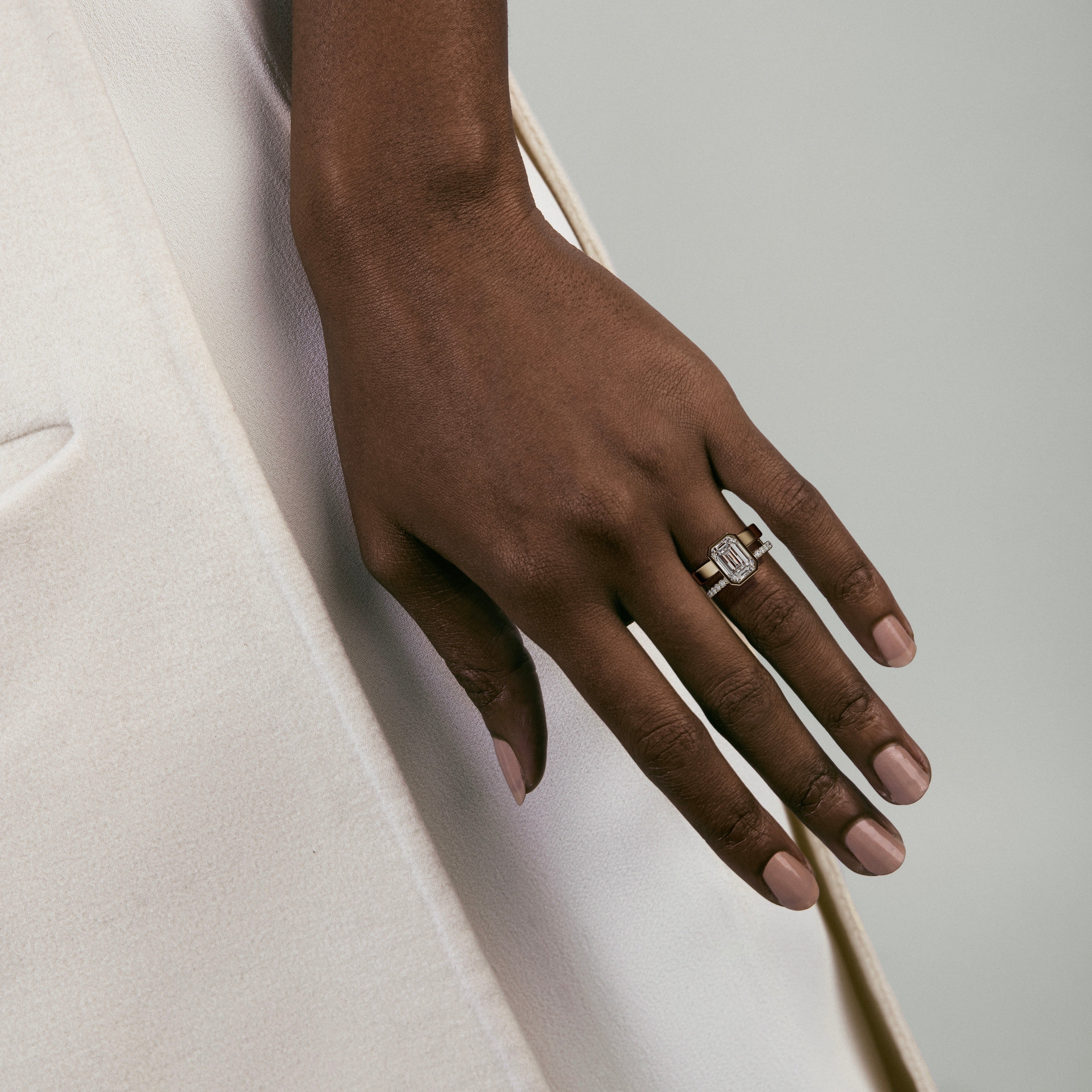 4.00 carat emerald-cut diamond engagement ring with bezel setting and pavé diamond eternity band worn on hand