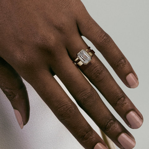 close view of 4 ct emerald-cut diamond bezel engagement ring on asymmetrical double band
