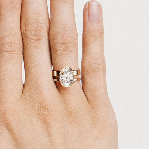 close view of 4 carat oval diamond bezel engagement ring on modern double band design