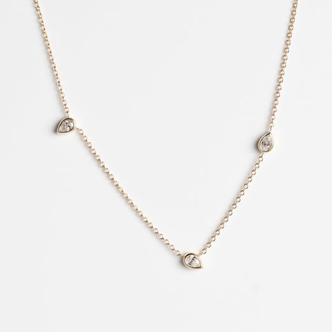 A delicate gold chain necklace featuring three small teardrop-shaped gold pendants, each set with white lab-grown diamonds, displayed against a clean white background.