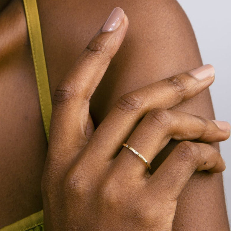 Thin flat gold wedding band with two round brilliant diamonds worn on hand