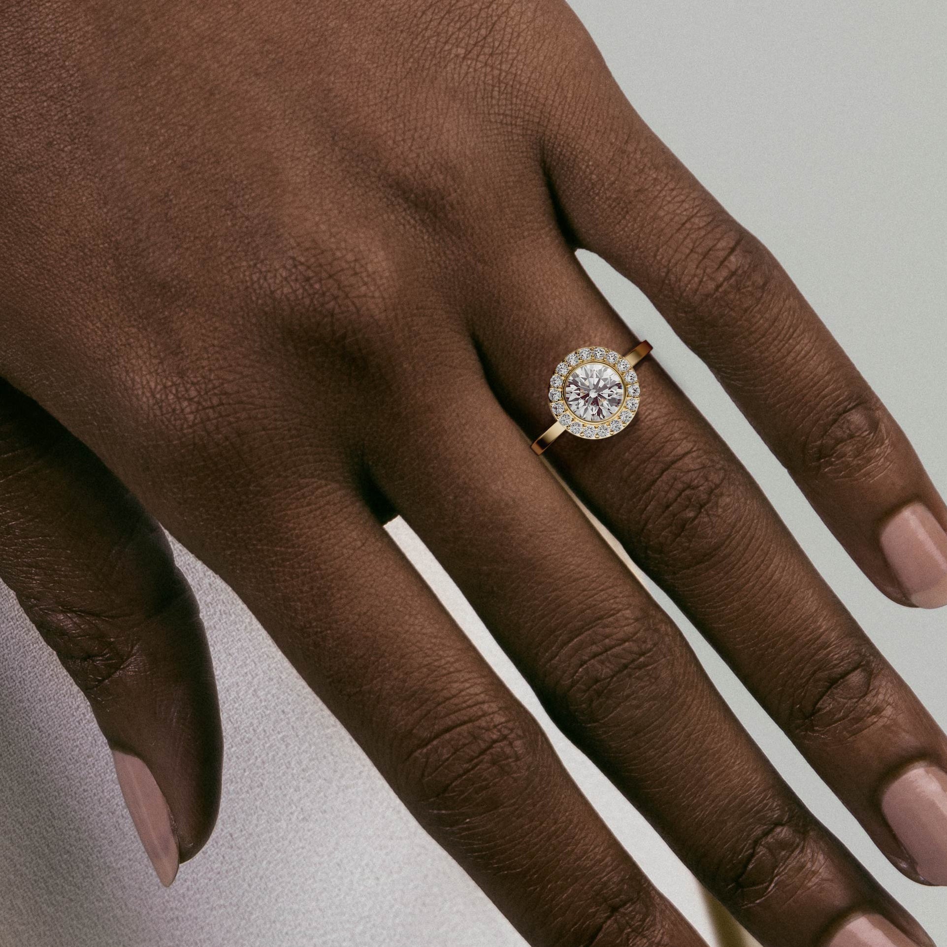 Close view of round brilliant diamond bezel halo engagement ring with pavé diamonds on slim band