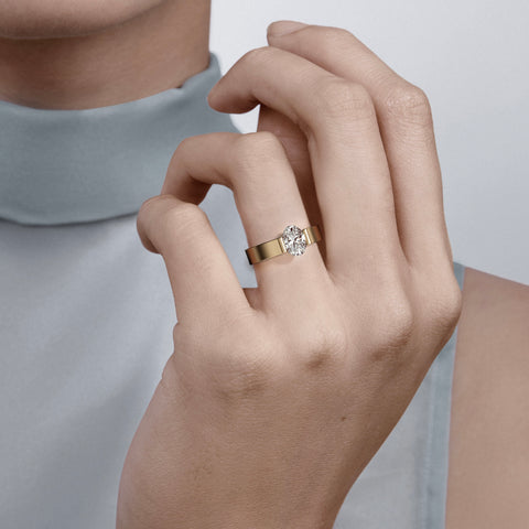 Close view of oval diamond in partial bezel on wide flat band